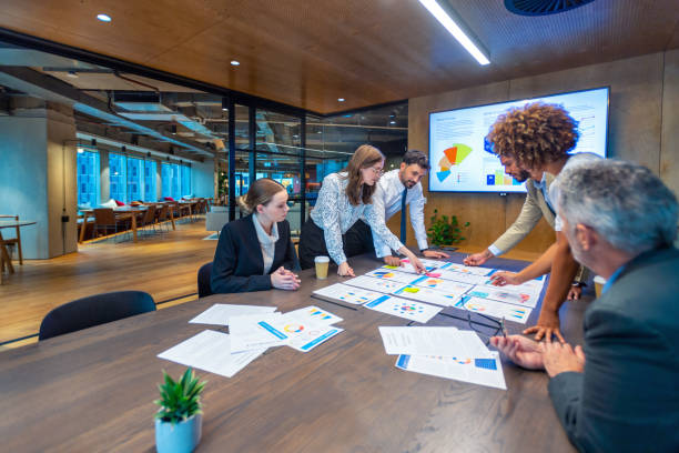 Paperwork and group of peoples hands on a board room table at a meeting