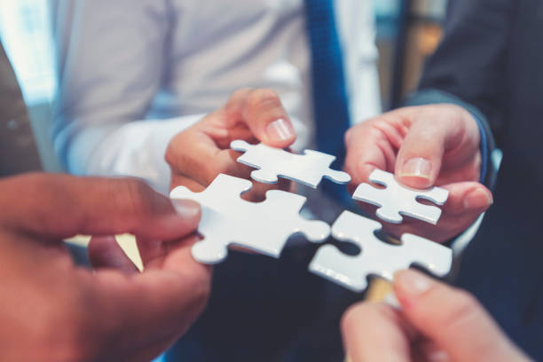 Group of business people holding a jigsaw puzzle pieces. Business Acquisition plan concept.