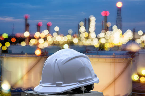 white safety helmet standing in front of oil refinery background