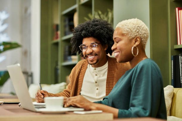 Smiling businessman and businesswoman discussing over laptop.